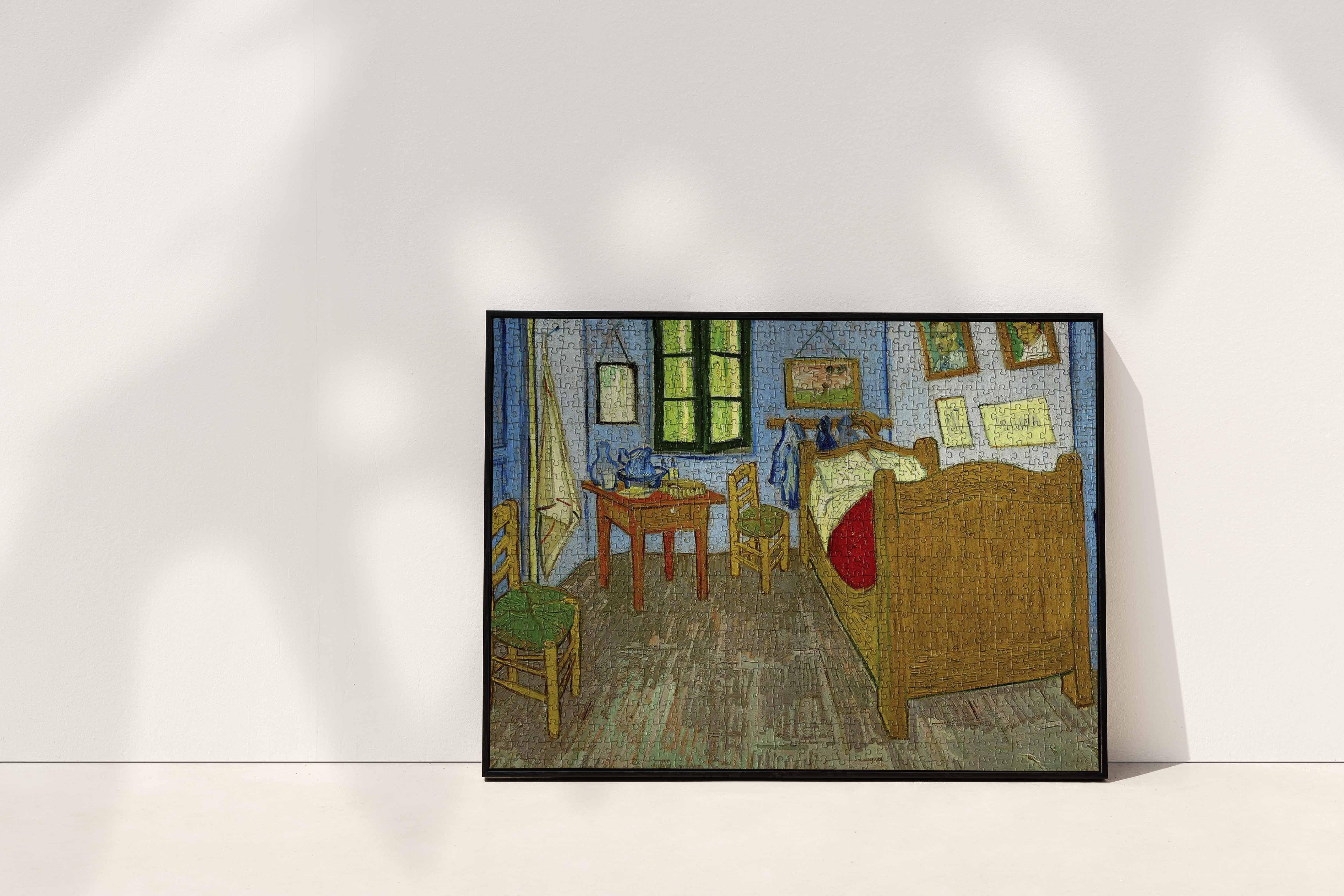A framed jigsaw puzzle of Van Gogh's Bedroom In Arles, showcasing the artist's iconic depiction of a cosy bedroom with vibrant hues and textured details.